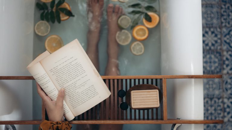 Person reading a book in tub of citrus and herbs